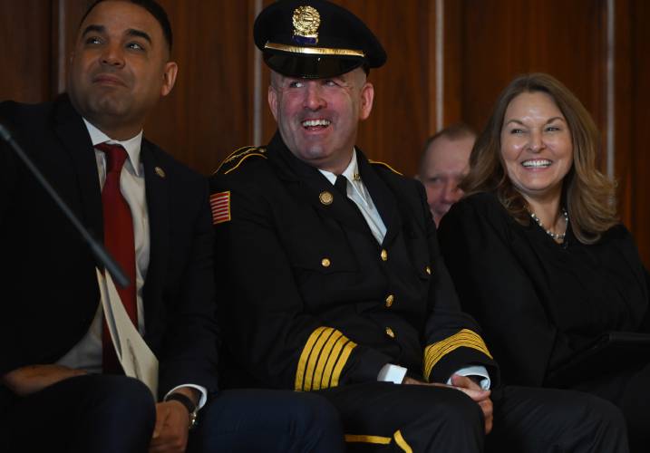 Brian Keenan, Holyoke’s new police chief, laughs during a speech by state Sen. John Velis at Keenan’s swearing in on Tuesday. To left is Holyoke Mayor Joshua Garcia and to right is Judge Tina Westcott Cafaro. 