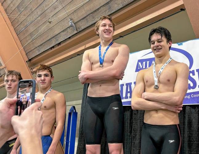 Northampton’s Reed Mitchell (middle) smiles on the podium after earning first place in the 100 breaststroke during Sunday’s Central/West Swimming Championships at Springfield College.