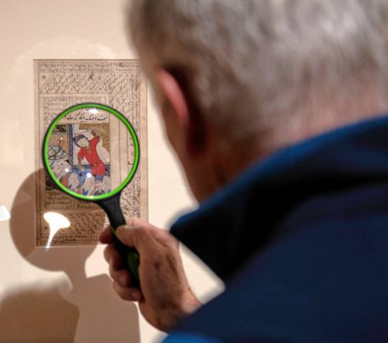 Jim Schwellenbach, of Portland, Maine, uses a magnifying glass to get a closer look at a detail in “Painting the Persianate World” at the Smith College Museum of Art.