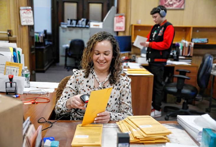Principal Clerk Jesenia Flores processes received mail-in ballots while temporary worker Jimmy Serrano sends out new ballots Friday afternoon at the Holyoke city clerk’s office.